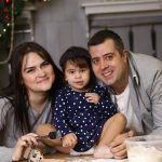 Happy family baking Christmas cookies together in a decorated kitchen.